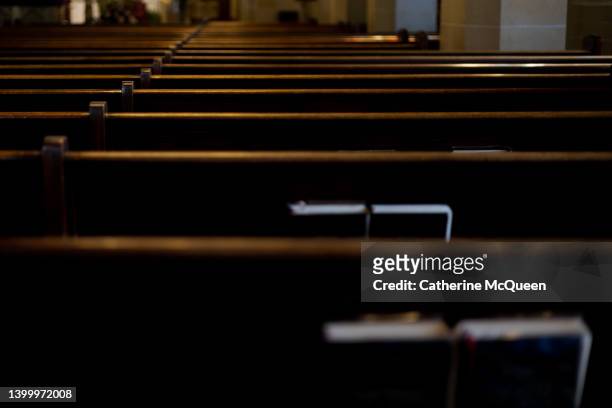intersection of religion & politics: rear view of rows of wooden pews with religious liturgy books stored in pew racks in church - minister clergy photos et images de collection