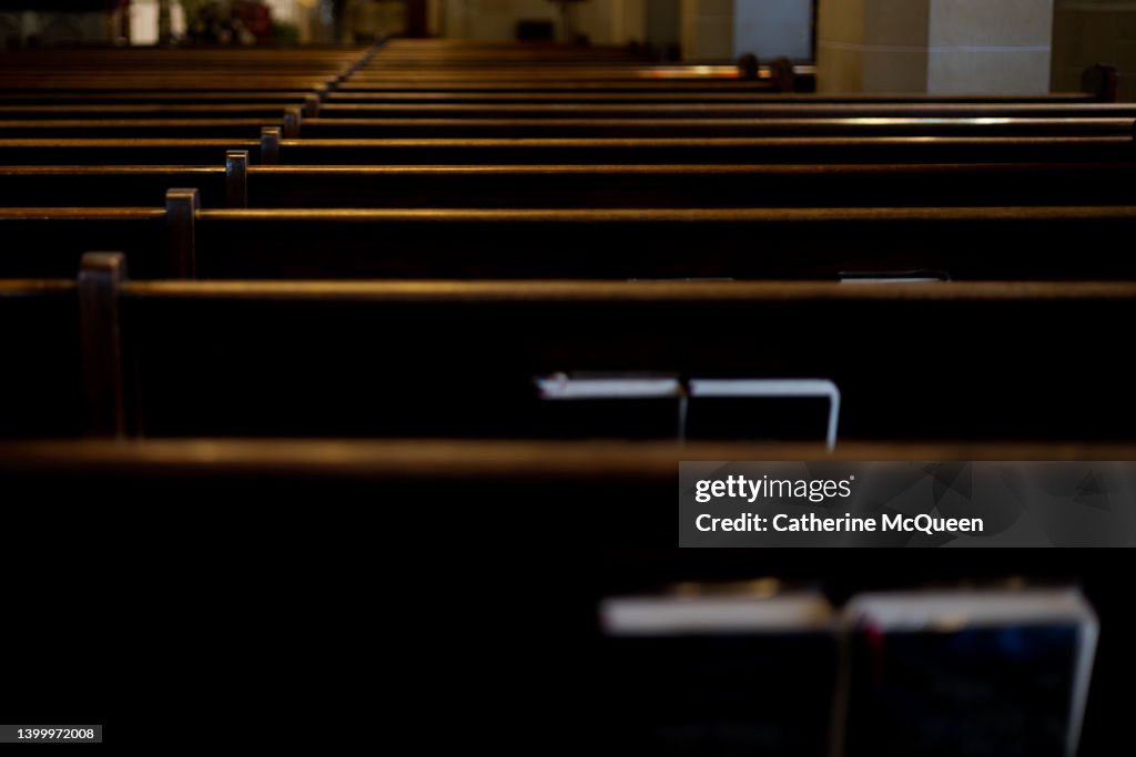 Intersection of religion & politics: rear view of rows of wooden pews with religious liturgy books stored in pew racks in church