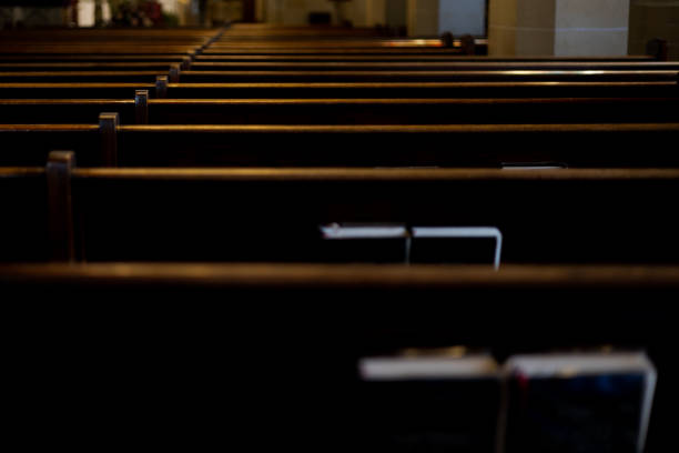 intersection of religion & politics: rear view of rows of wooden pews with religious liturgy books stored in pew racks in church - ministério - fotografias e filmes do acervo