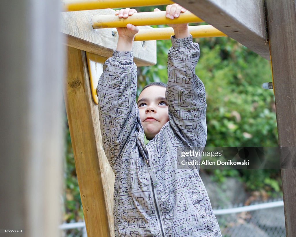 Boy hanging from monkey bars