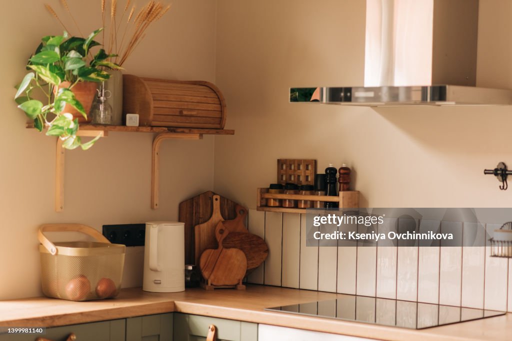 Modern interior design at white contemporary kitchen in loft style. Glossy cabinet with built in household appliance, electric stove, oven, sink on worktop and extractor hood on grey wall