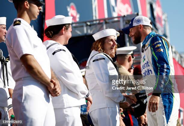 Ross Chastain, driver of the Advent Health Chevrolet, shakes hands and shares a laugh with a service member during driver intros prior to the NASCAR...