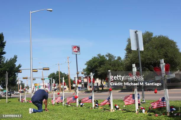 Man kneels as he prays at a memorial for the victims of the Robb Elementary mass shooting on Main Street on May 29, 2022 in Uvalde, Texas. 19...