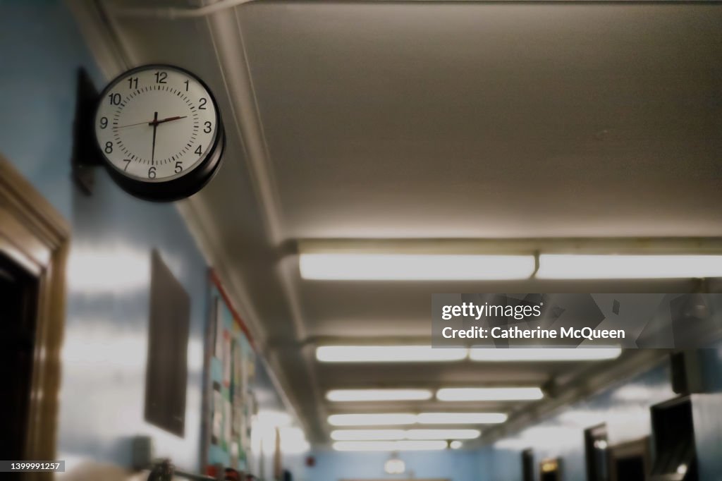 Partial darkened view of school corridor with defocused exit sign in the background