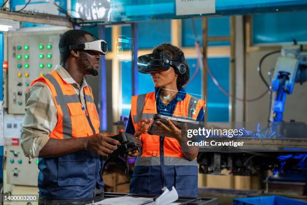 female industry engineer using the digital tablet  for  send information to server in robot system while her teamwork teaching robot and in production line. the digital display had shown about the 
 innovation of manufacturing with technology concepts. - information security stock-fotos und bilder