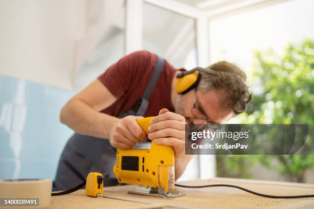 carpinteiro macho usando quebra-cabeça enquanto cortava um buraco para uma pia de cozinha - serra tico tico serra elétrica - fotografias e filmes do acervo