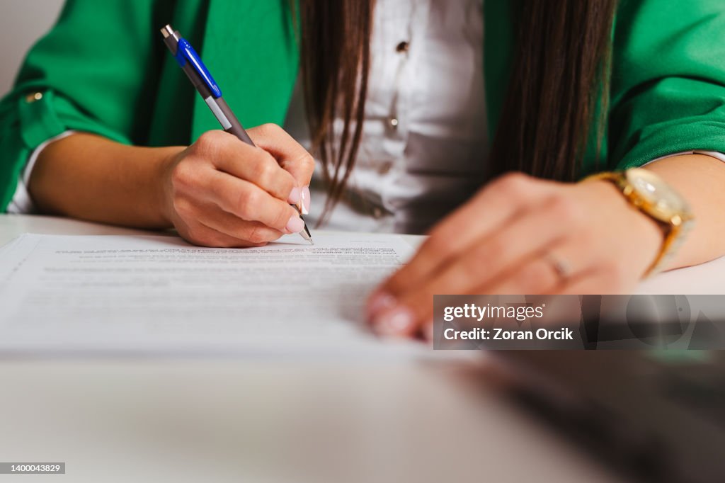 Businesswoman's hand with pen completing personal information on a form