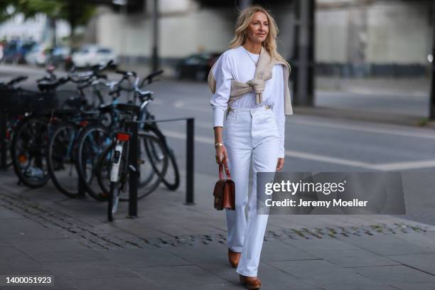 Sue Giers is seen wearing Ralph Lauren brown leather clogs, Celine white denim jeans, SoSue white long shirt and SoSue beige sweater and Savette...