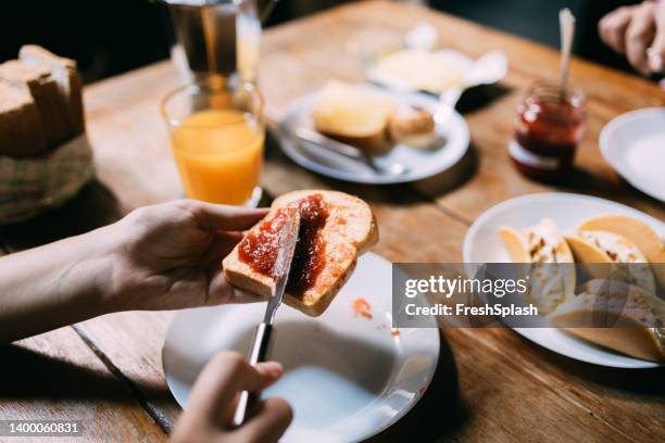 donna anonima che sparge marmellata sul pane - jelly foto e immagini stock