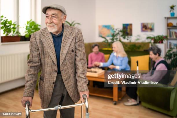 an elderly disabled man walking slowly with walker in a nursing home - assisted living community stock pictures, royalty-free photos & images
