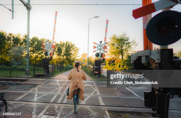 woman riding bicycle near the railway crossing - level crossing stock pictures, royalty-free photos & images