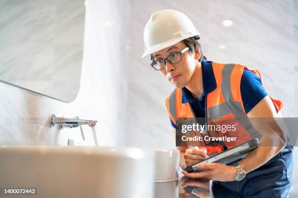 a japanese home inspector will look at the structural components of the bathroom. he had inspected home sanitary ware, make sale reports and input data into the digital tablet. - plumber tablet stock pictures, royalty-free photos & images