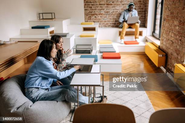 colleagues using laptop on a break from work in office chill room - workplace wellbeing stock pictures, royalty-free photos & images