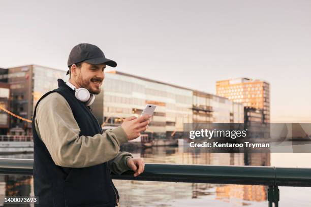 a man watching his mobile phone in a city environment - mane stock pictures, royalty-free photos & images