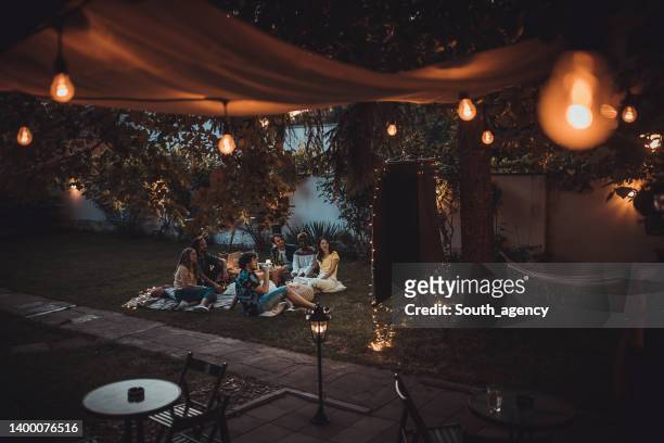 friends watching movie on the video projector in the backyard garden - backyard movie stock pictures, royalty-free photos & images