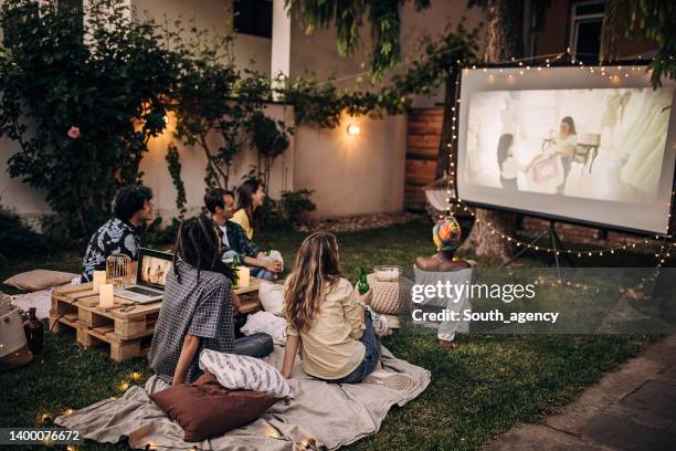 freunde, die auf dem videoprojektor im hinterhofgarten film schauen - beamern stock-fotos und bilder