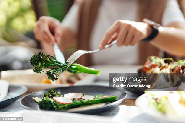 cropped shot of young woman eating organic salad at outdoor restaurant - geniessen teller essen stock-fotos und bilder