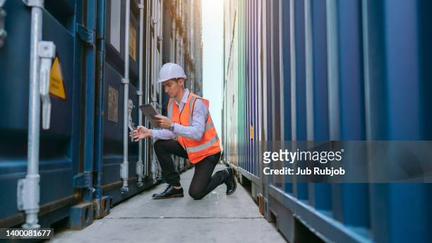 young man engineer working in container cargo warehouse at terminal commercial port for business logistics, import export or freight transportation - marine engineering stock pictures, royalty-free photos & images