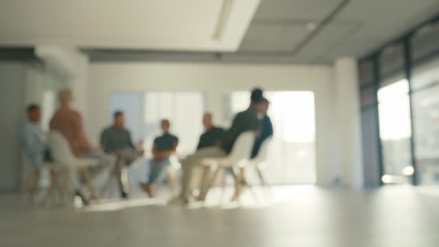 Male group support therapy. Blur therapist, counselor or coach talking to a group of men in rehab. Diverse people in treatment for mental health, recovery, drug or alcohol addiction