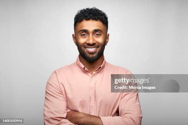 smiling bearded businessman with arms crossed - man standing against grey background foto e immagini stock