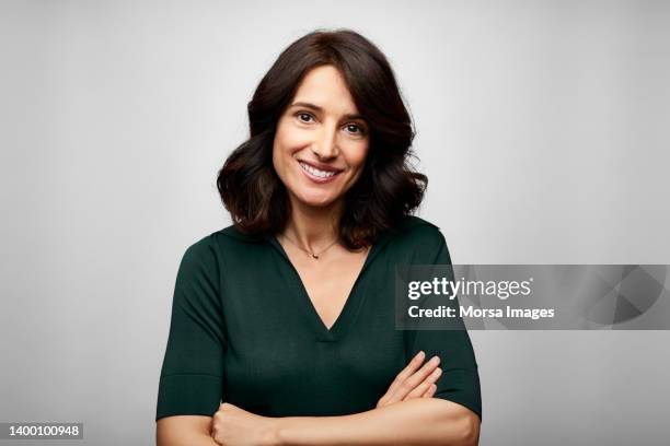smiling brunette businesswoman with arms crossed - woman fotografías e imágenes de stock