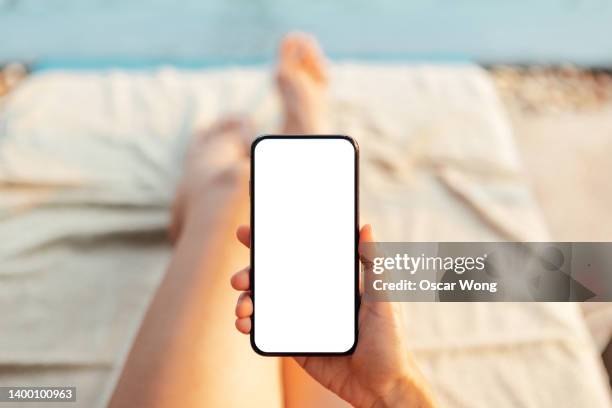 cropped shot of female hand holding smart phone at poolside - hands holding smart phone stock-fotos und bilder