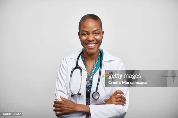 african american female doctor with arms crossed over white background - black doctor stock pictures, royalty-free photos & images