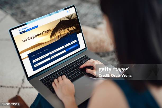woman using laptop to book flight tickets and plan holiday - booking hotel foto e immagini stock