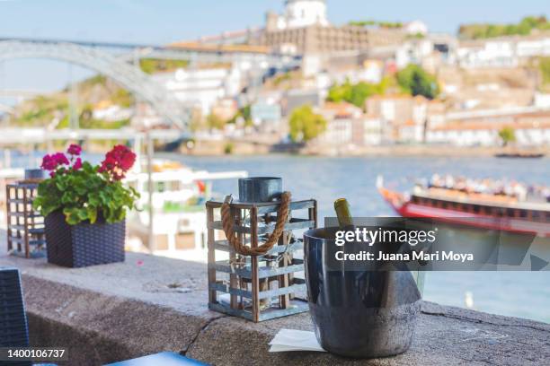 port wine in a champagne cellar in a restaurant next to the douro river, with the luis i bridge and a pleasure boat in the background - porto portugal wine stock pictures, royalty-free photos & images