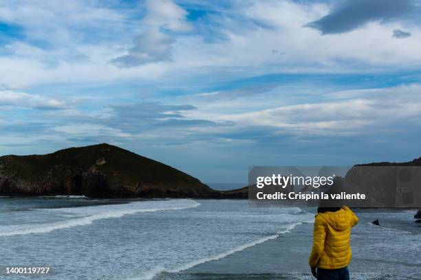 rear view woman with yellow anorak contemplating the sea in winter - roupa quente imagens e fotografias de stock
