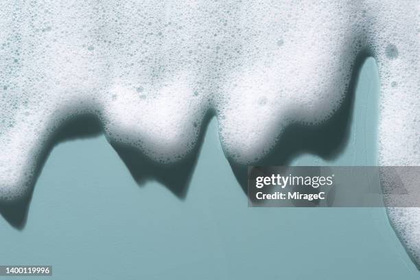 white soap foam flowing on blue - bathroom clean closeup stock-fotos und bilder