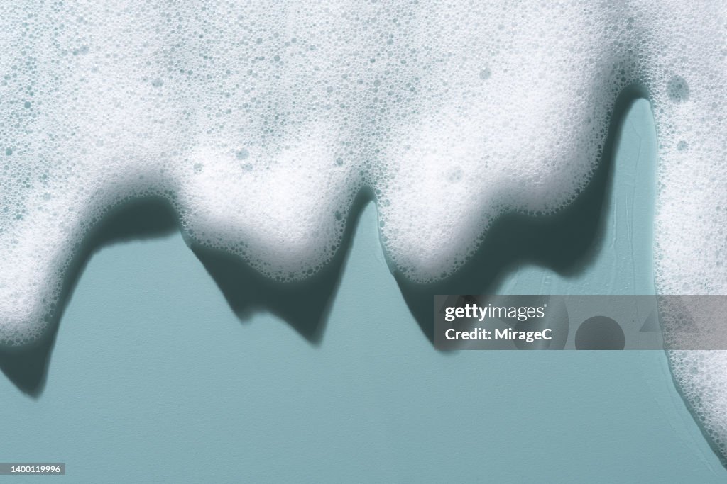 White Soap Foam Flowing on Blue