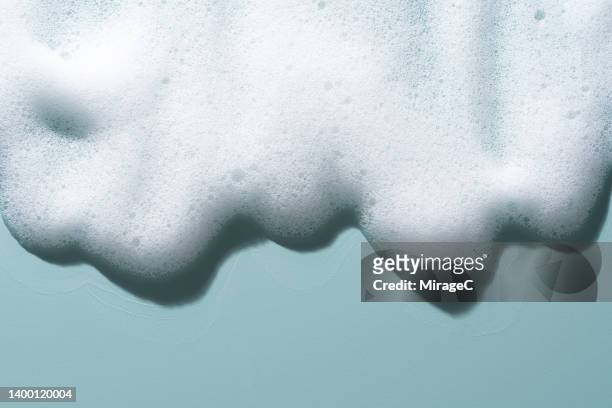 white soap foam flowing on blue - shaving cream stock-fotos und bilder