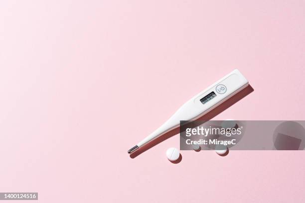 thermometer displays 38.5℃ with white pills on pink - paracetamol stockfoto's en -beelden