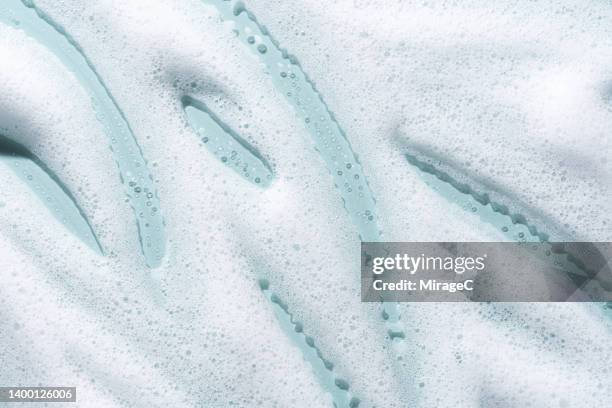 white foam soap suds on light blue - shampoo stock-fotos und bilder