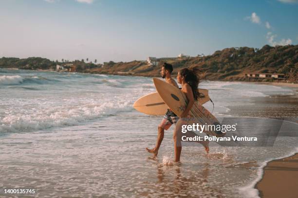 pareja corriendo al mar - surfboard fotografías e imágenes de stock