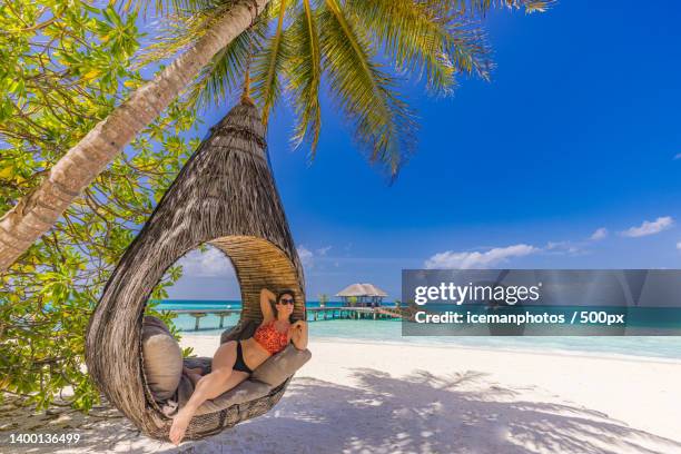 woman sitting on swing at beach against sky,ari atoll,maldives - ari stock-fotos und bilder