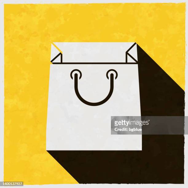 stockillustraties, clipart, cartoons en iconen met shopping bag. icon with long shadow on textured yellow background - goodie bag