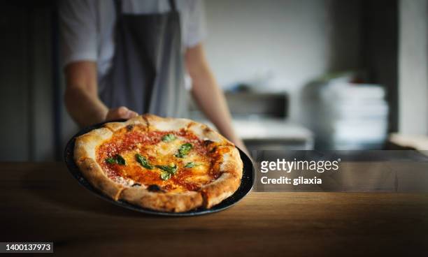 pizza chef serving freshly baked pizza. - pizza stockfoto's en -beelden