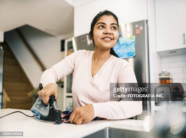 young indian woman ironing - stereotypical homemaker stock pictures, royalty-free photos & images