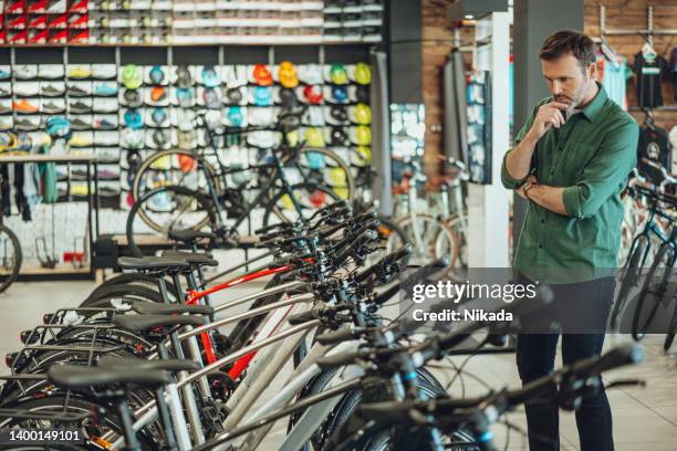 mann checkt fahrräder im fahrradladen aus - buying a bike stock-fotos und bilder