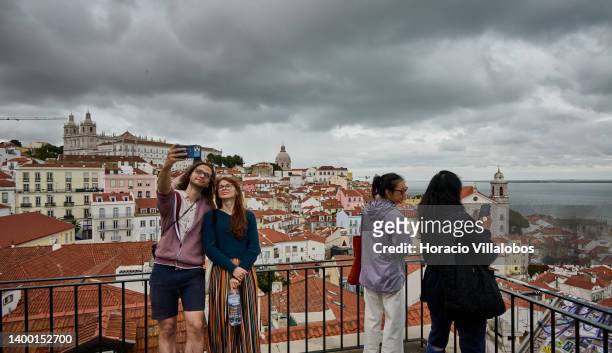 Tourists selfie at the Miradouro of Portas do Sol, a favorite spot for city visitors, on May 30, 2022 in Lisbon, Portugal. Tourism in Portugal is...