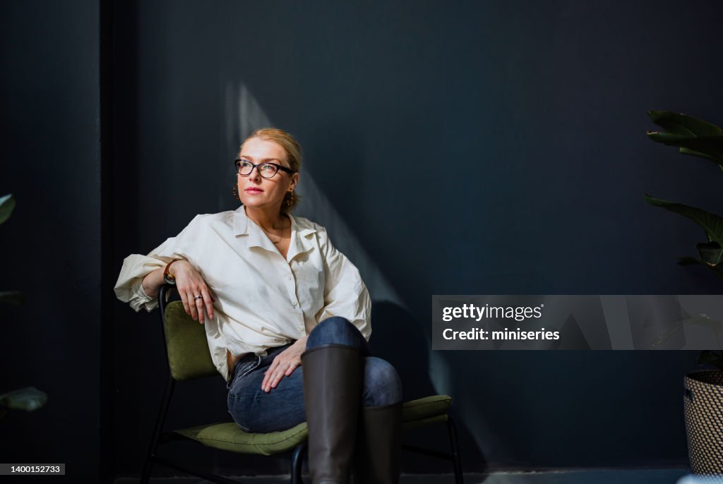 Porträt einer ernsthaften Geschäftsfrau, die im Büro sitzt und denkt