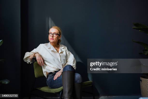 portrait of serious business woman sitting in the office and thinking - chair business stockfoto's en -beelden