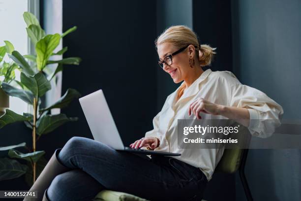 glückliche geschäftsfrau mit laptop-computer im büro - business laptop stock-fotos und bilder