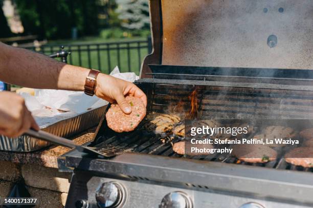 man cooking hamburger on grill - karzinogen stock-fotos und bilder