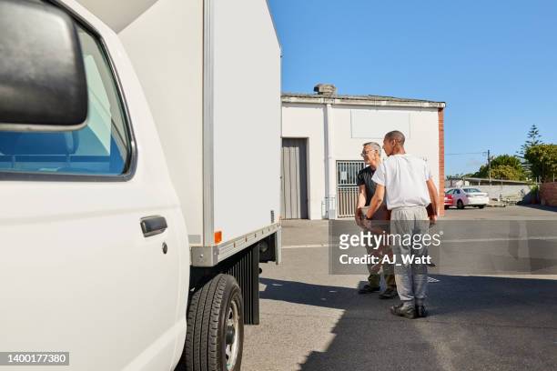 zwei arbeiter, die einen holztisch tragen und auf einen lieferwagen laden - old truck stock-fotos und bilder
