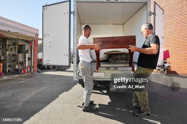 zwei schreiner laden einen holztisch auf einen lieferwagen - körperliche aktivität stock-fotos und bilder