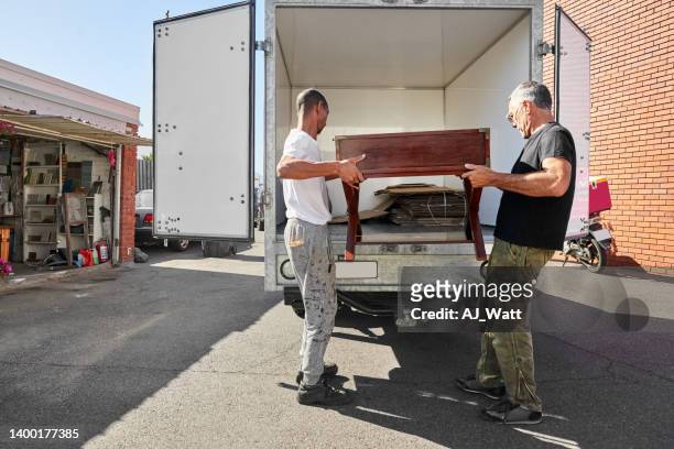 dos carpinteros cargando una mesa de madera en una furgoneta de reparto - old truck fotografías e imágenes de stock