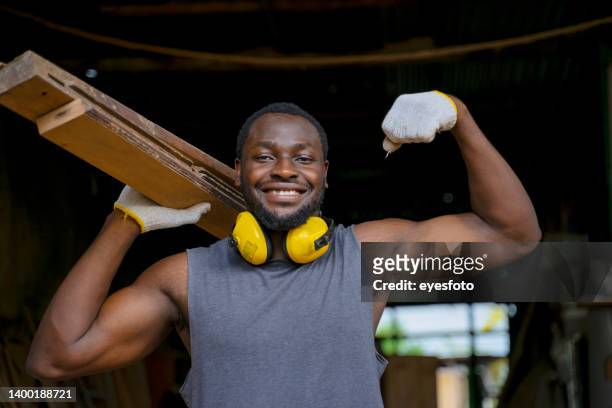 carpenter is working in workshop. he is working with plank. - man muscular build stock pictures, royalty-free photos & images